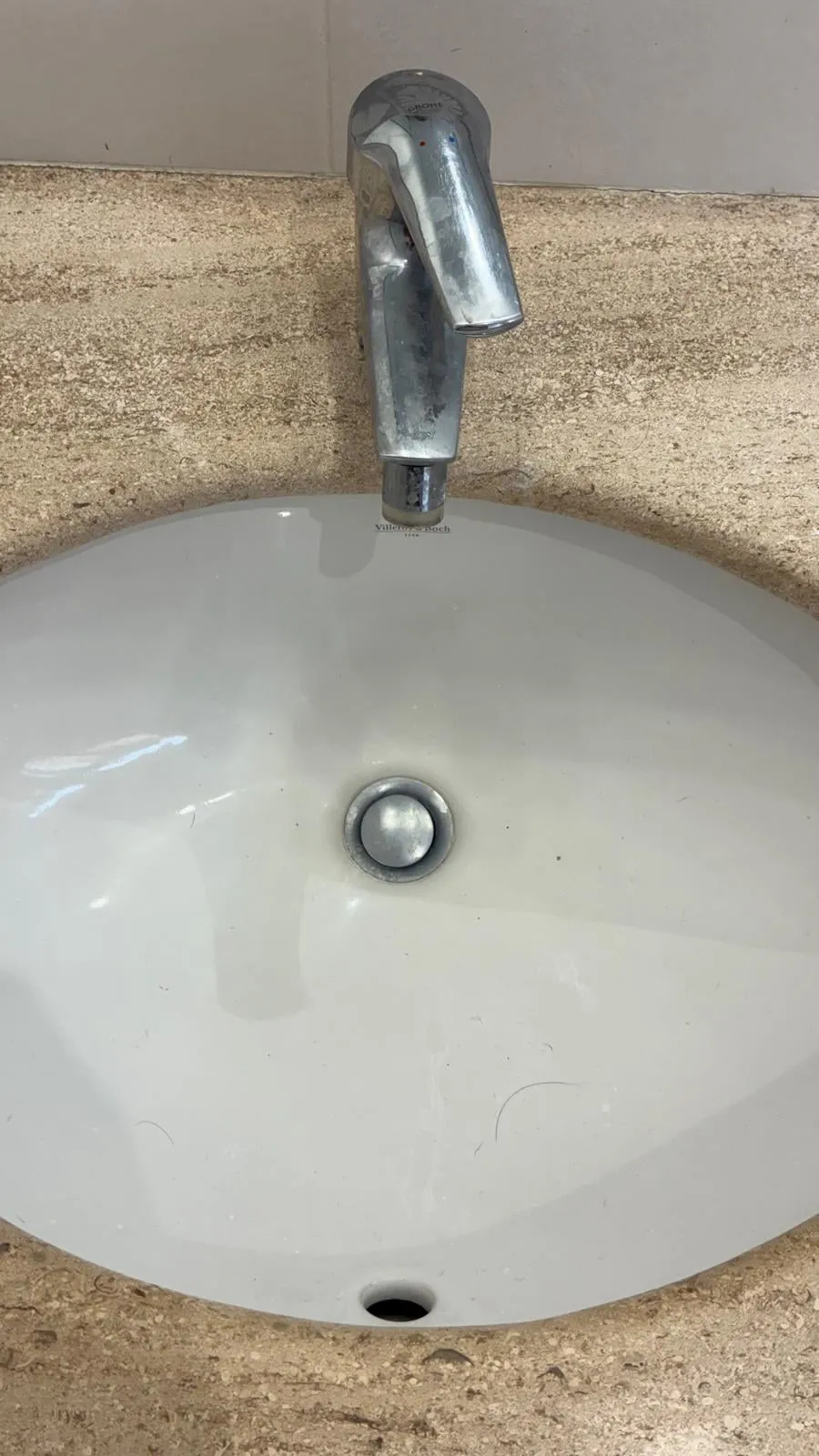Vasque en pierre et mitigeur entartrés par le calcaire, avant détartrage